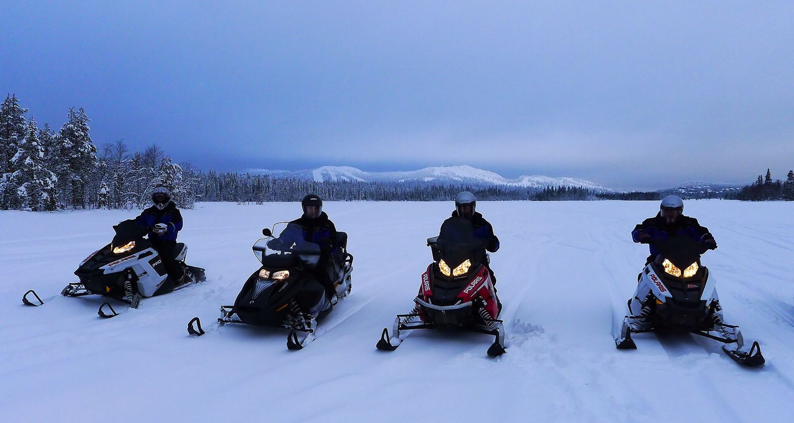 Group on snowmobiles on a snowy Lapland plain