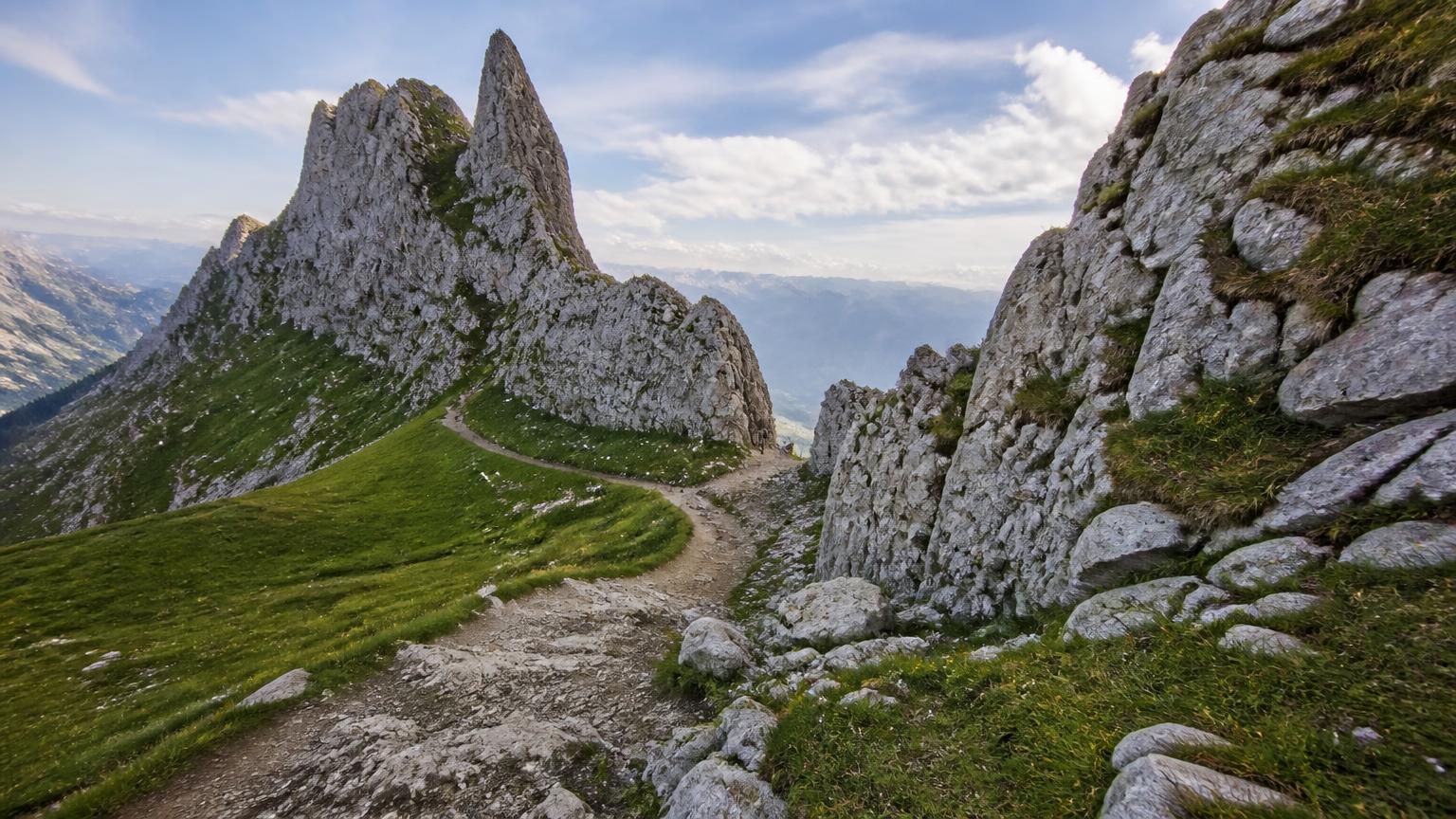Dramatic limestone ridges and green alpine meadows at Saxer Lücke in the Swiss Alpstein